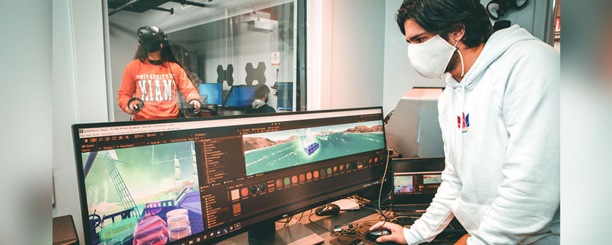 Programmer and first-year medical student Varun Krishnan edits a VR app called "Synesthesia," while its creator, University of Miami senior Léa Dorne, tests it out in the background. Photo: Mike Montero/University of Miami