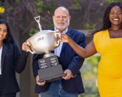 Debaters Iman Sami, left, and Delphine Djomo, right, and debate coach David Steinberg pose with the ACC Championship trophy. Photo: Evan Garcia/University of Miami