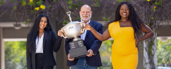 Debaters Iman Sami, left, and Delphine Djomo, right, and debate coach David Steinberg pose with the ACC Championship trophy. Photo: Evan Garcia/University of Miami