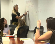 Hannah Artman (standing) giving a guest lecture on focus group methodology at the University of Miami School of Communication.