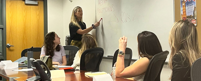 Hannah Artman (standing) giving a guest lecture on focus group methodology at the University of Miami School of Communication.