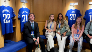 Students sit in the locker room of FC Chelsea during their tour of Stamford Bridge, the stadium where the team plays, after they learned all about the communication techniques the club utilizes.