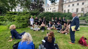 Sitting on a grassy knoll, students converse with Birgit Maaß, UK correspondent for Deutsche Welle, who shared her professional experience and insights.