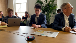 Elliott Wyndorf, center, sits next to Professor Treaster, far right, during a briefing at The New York Times.